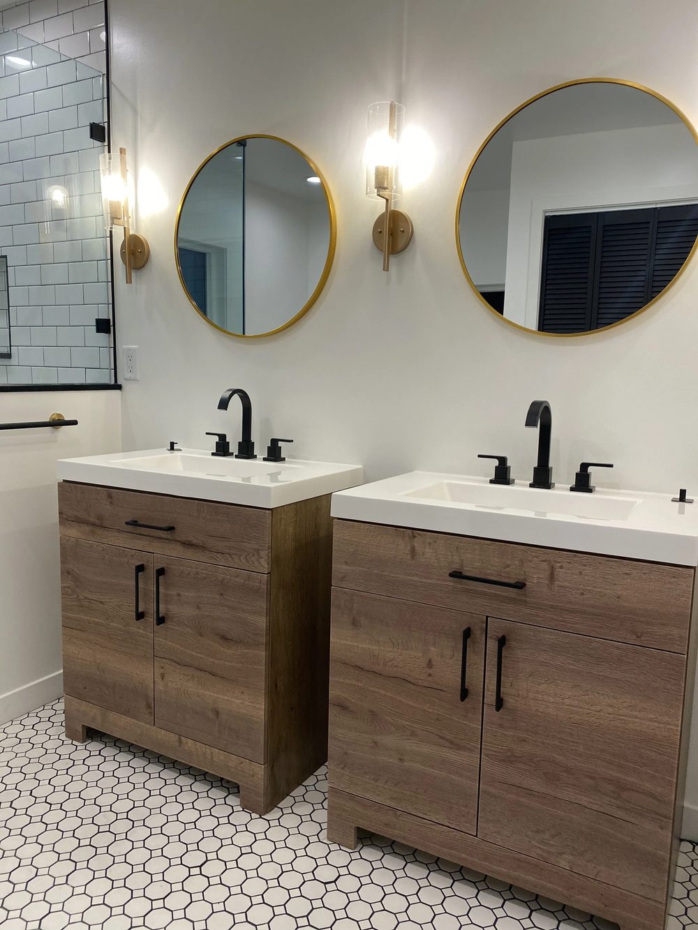 Finished bathroom with a custom vanity and gold mirrors